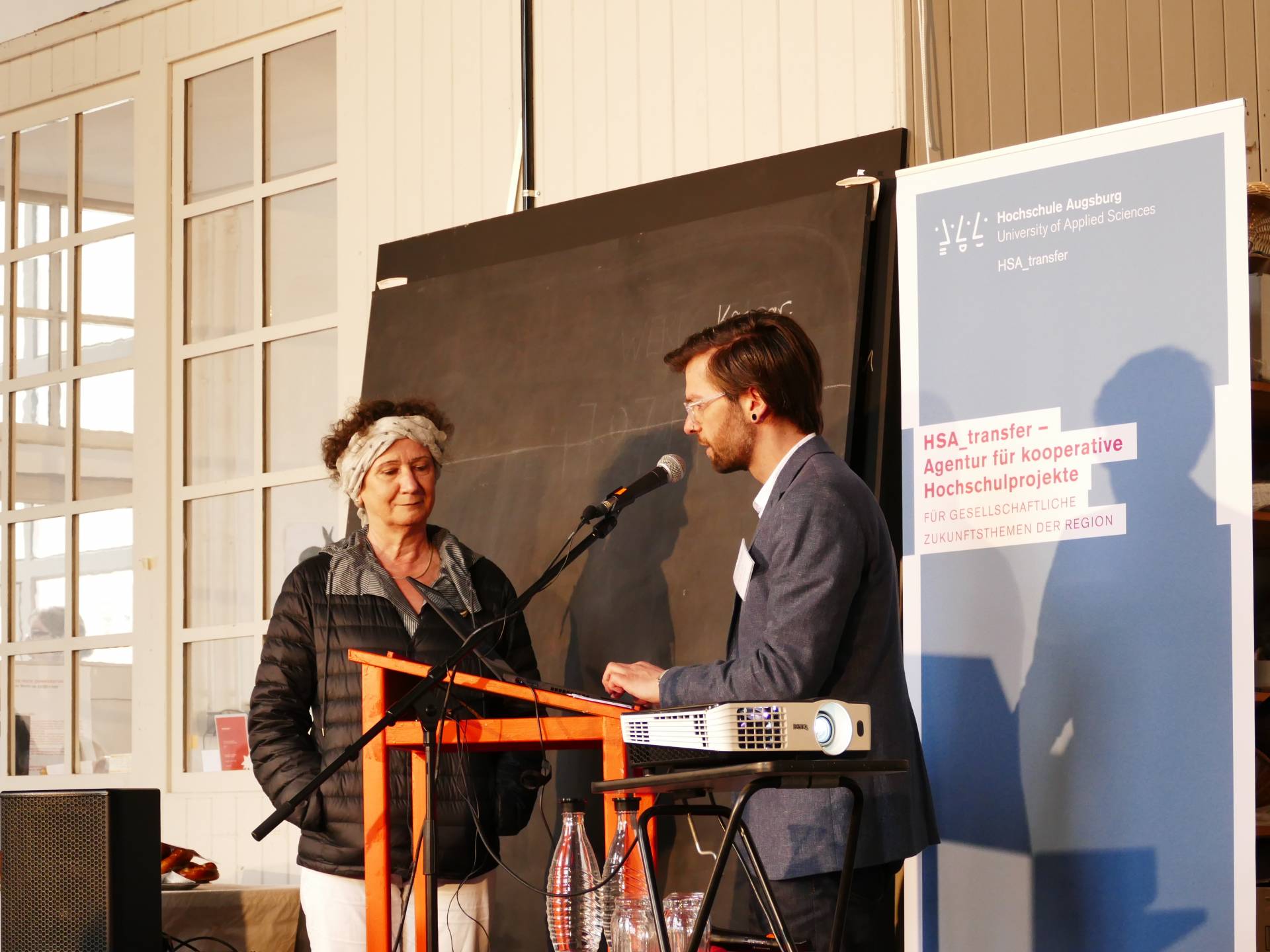 Moderator Eyk Henze, Referent für Netzwerke der HSA_transfer, und Juliane Stiegele von der UTOPIA TOOLBOX eröffnen das HSA_tranfer | Forum.