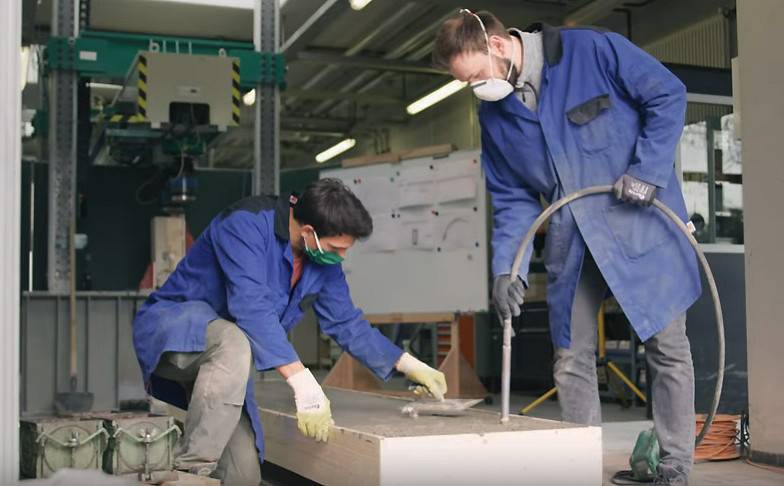 Zwei Mitarbeiter des Baustofflabors bereiten einen Holz-Beton-Träger vor