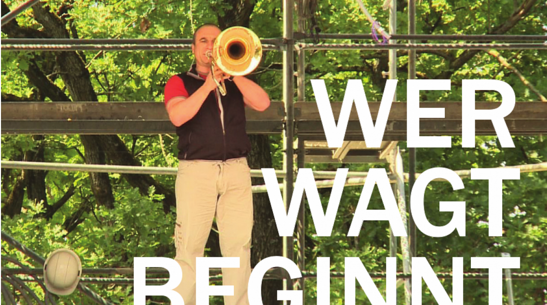 Trompeter auf Baugerüst, darüber der Schriftzug "Wer wagt beginnt".