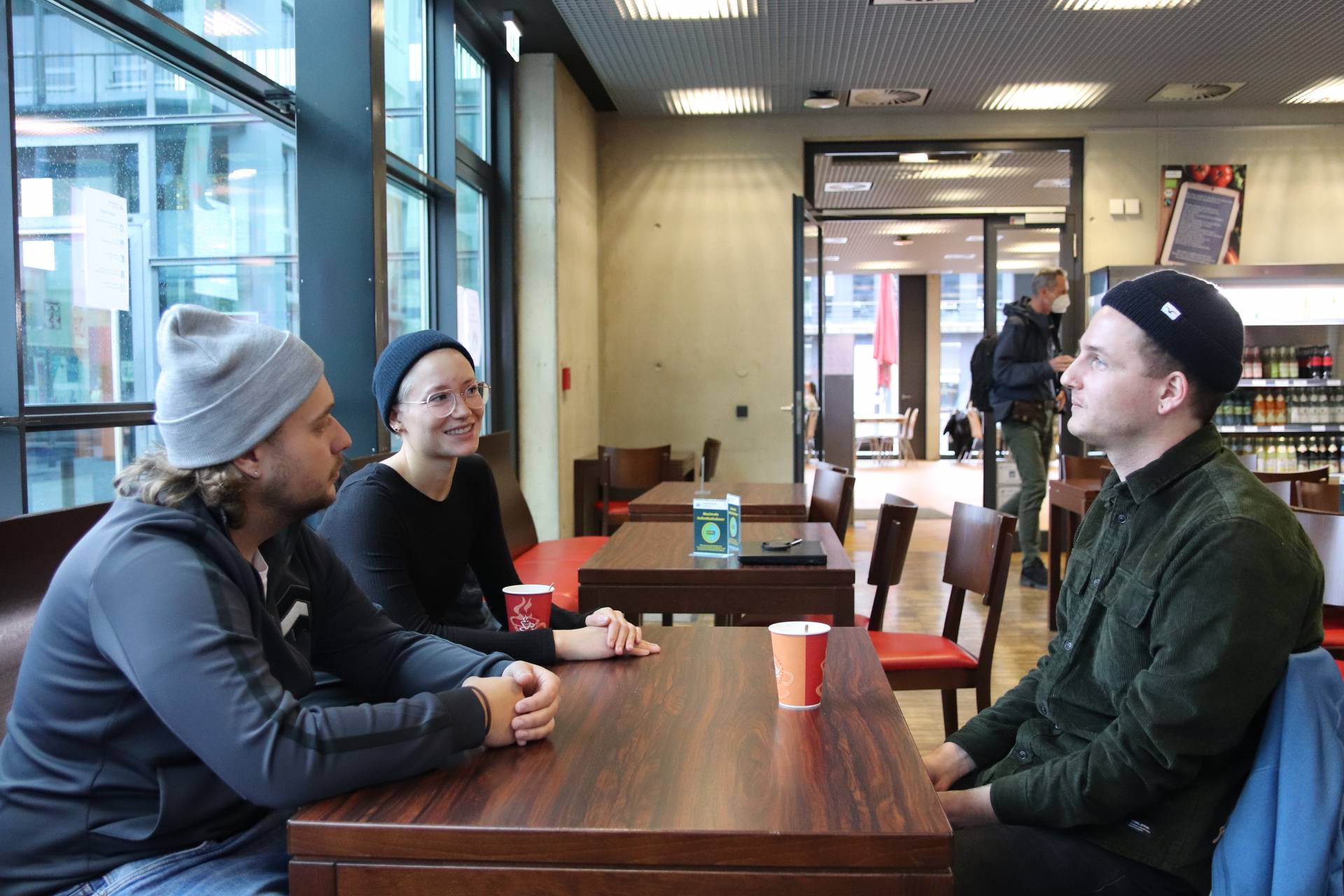 Simon (rechts), Kilian und Carolin (Mitte) in der Cafeteria im Gespräch