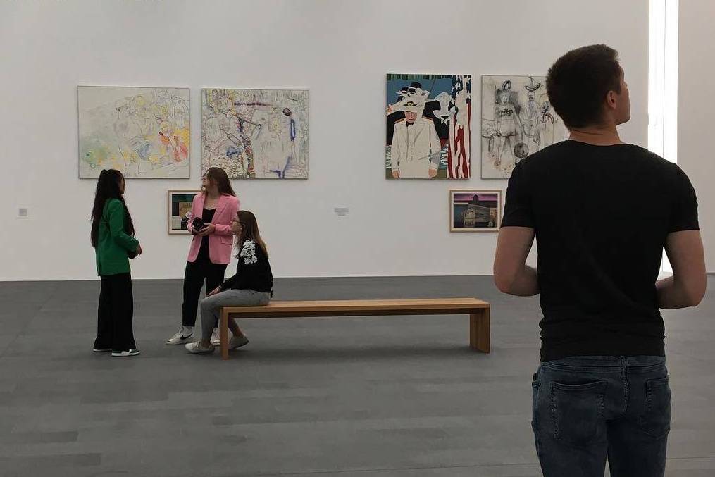 Personen in einer Ausstellungshalle mit Gemälden