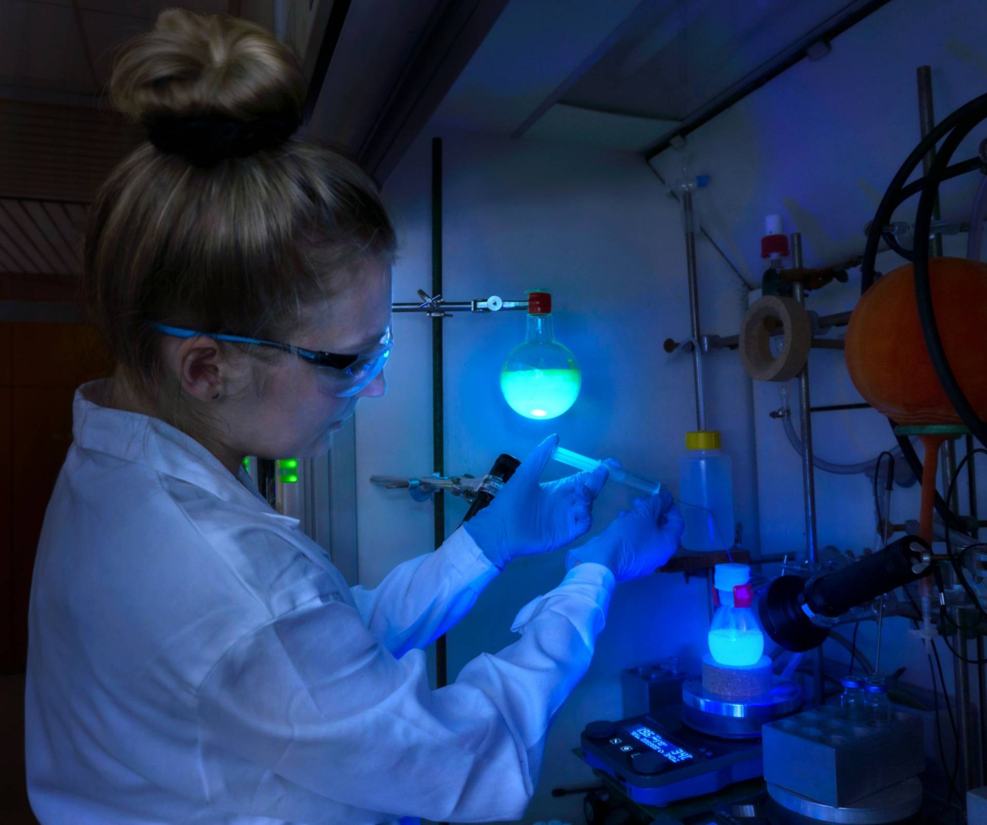 Studentin arbeitet in einem dunklen Labor mit fluoriszierenden Substanzen